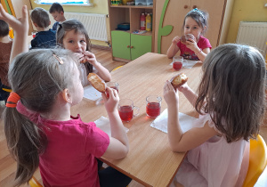 Grupa dzieci przy stoliku je pączki.